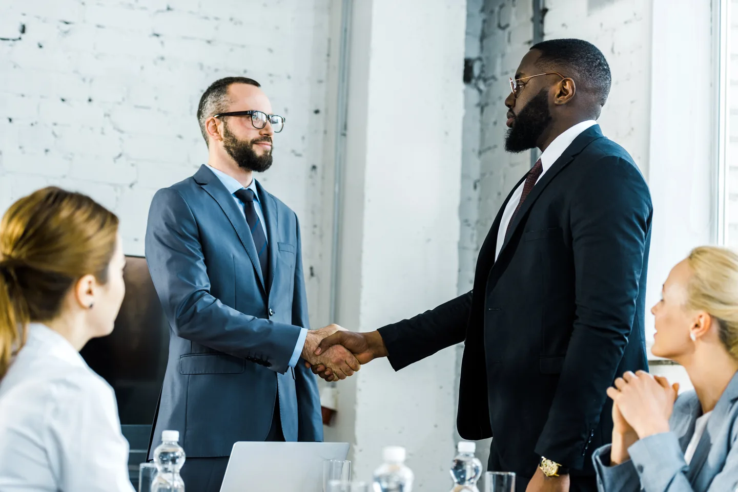Businessmen shaking hands during a meeting with colleagues.